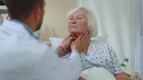 Caring Doctor Examines Elderly Woman in Hospital Bed