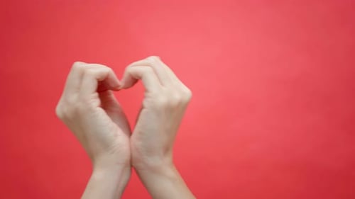 Hands Forming Heart Shape on Red Background