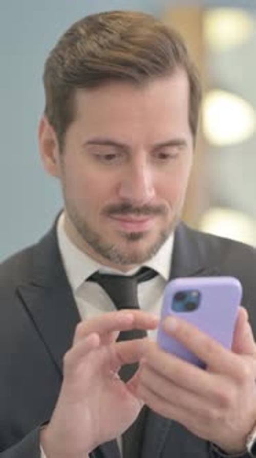 Businessman Celebrates Success While Using Mobile Phone