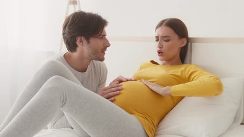 Pregnant Woman in Labor Lying on Bed with Partner