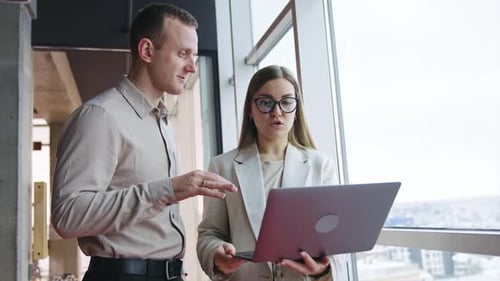 Professionals Discussing Laptop in Modern Office