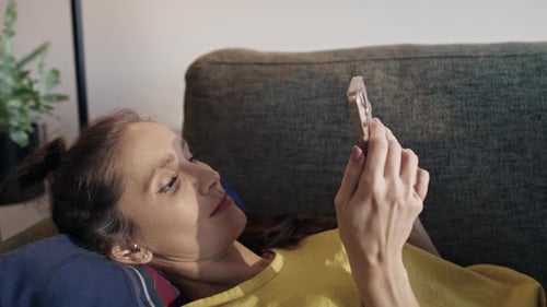 Woman Relaxes on Couch Using Cellphone