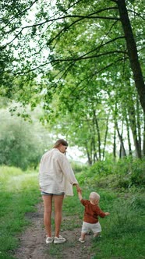 Rear view of a woman in shirt and shorts and baby standing on the path.