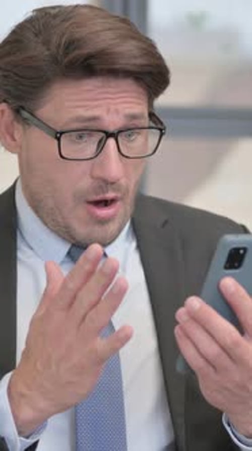 Surprised man using smartphone in office setting