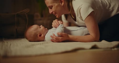 Loving Woman Plays with her Baby on Blanket