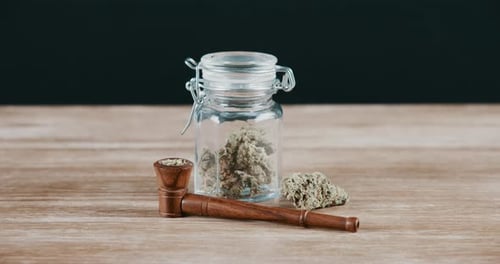 Smoke, pipe and marijuana in a jar on a table in studio on a black background for cbd medication