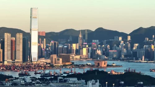 High skyline of Hong Kong city illuminated by the setting sun among the high mountains of green natu