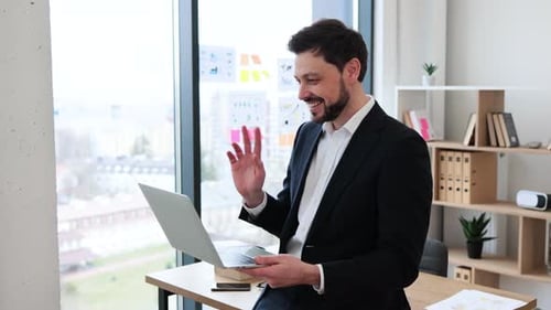 Professional Man in Suit Having Online Meeting Using Laptop in Office Setting