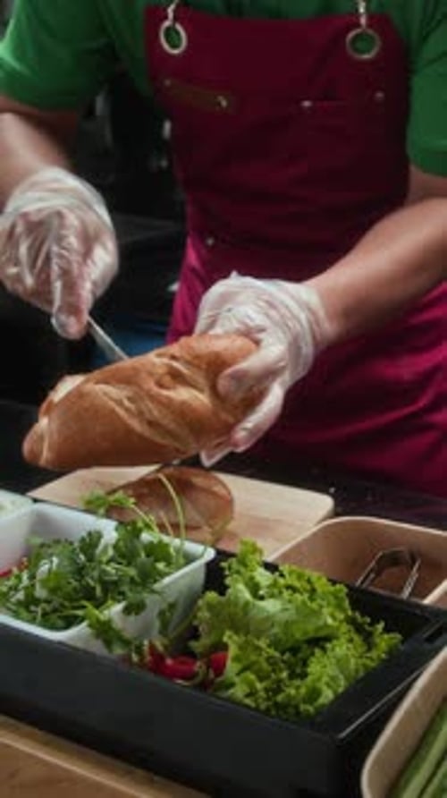 Unrecognizable Street Cafe Employee Adding Fillings in Bun
