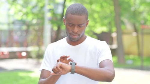 Young African Man Using Smartwatch Outdoor in Park