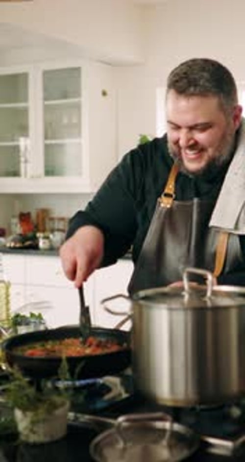 Man Cooking Food on Stove in Kitchen