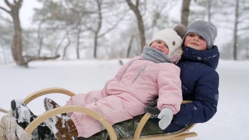 Children Sledding in Snow With Family