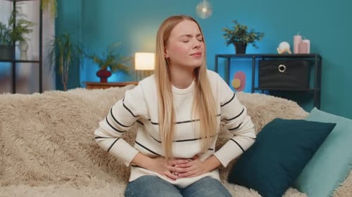 Woman Experiencing Stomach Pain While Sitting on Couch