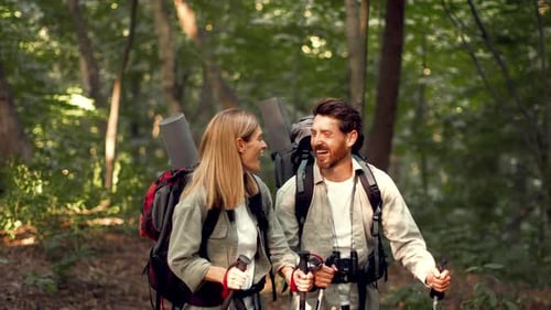 Couple Enjoying a Hiking Adventure in a Green Forest With Backpacks and Trekking Poles