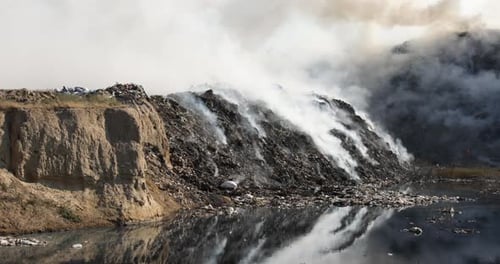 Burning Trash Landfill Next to Water