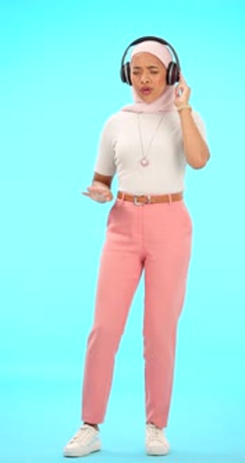 Headphones, dance and Muslim woman in studio on blue background listening to music, song and audio