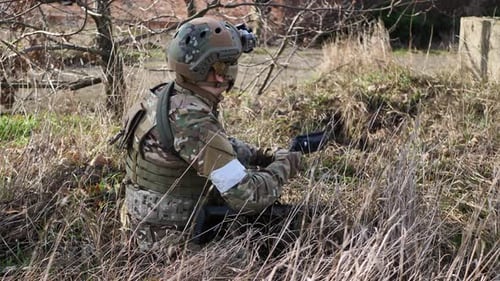 Soldier Aims Firearm in Rural Field