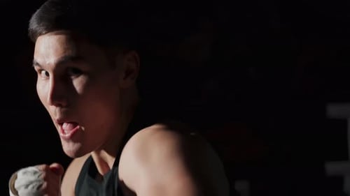 Portrait of a Man on a Dark Background An Athlete Does a Shadow Fight Slow Motion in Low Key