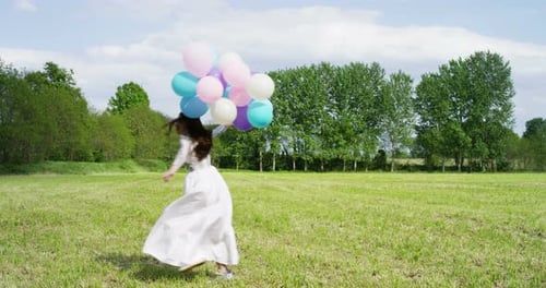 Woman Runs With Balloons in Sunny Field