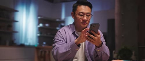 Adult Uses Smartphone at Table Indoors
