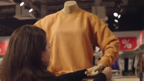Woman Seller Dress on Mannequin Orange Sweatshirt in Retail Sales Store Clothing
