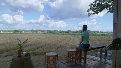 Vue à grand angle prise à main fixe d'une femme assise sur le banc d'un café-bistrot tout en regardant un