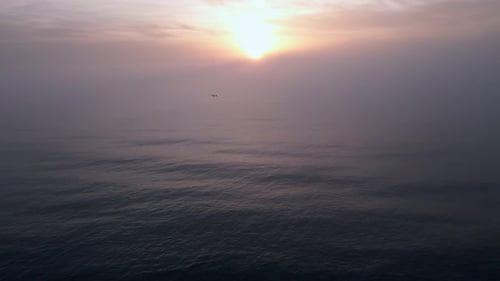 Vue aérienne d'une mer au lever du soleil avec une couverture de brouillard matinal et des rayons de soleil matinaux qui brillent