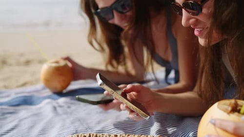 Cheerful Girls Tan Surf Internet on Phones at Sandy Beach Happy Ladies Sunbathing Texting on Devices