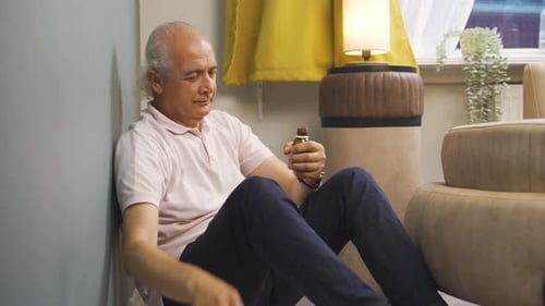 Man Taking Medication While Sitting on Floor