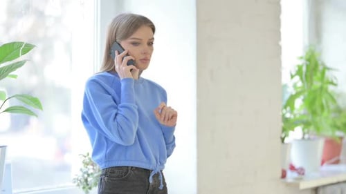 Woman Talking on Phone Indoors by Bright Window