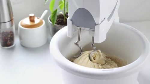 Mixer stirs the dough in a spinning bowl. A stationary mixer with a bowl kneads the dough