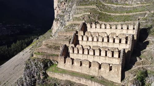Aerial pan right of historic town site of Ollantaytambo cut out of hillside in Peru