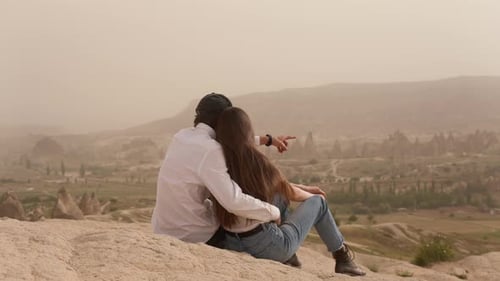 Couple of Man and Woman Sit and Hug on Mountain Slope Above Valley
