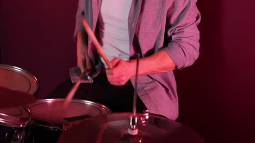 Man playing drums with drumsticks in studio, closeup