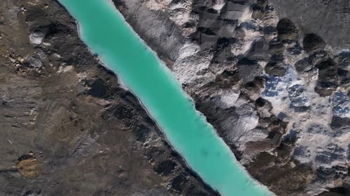 A Striking Contrast Between Turquoise Water and Dark Rugged Terrain at a Tailings Lake The