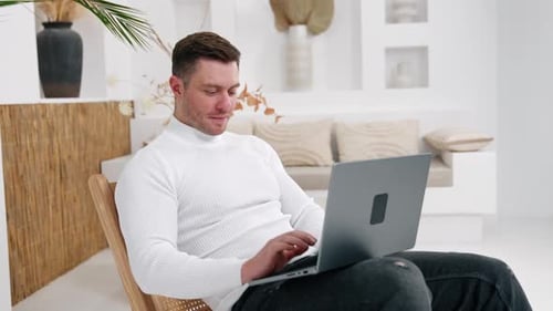 Young Man Works on Laptop in Bright Room