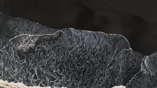 Waves Crash on Black Sand Beach Shore - Top Down Aerial Long Shot. Abstract and Minimal