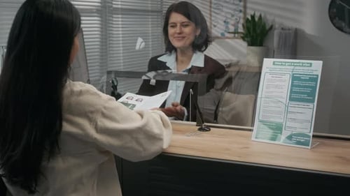 Woman Submitting Documents at Visa Agency and Talking to Officer