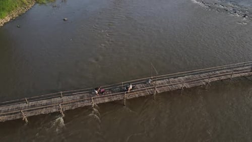 Aerial footage shows a wooden bridge spanning the Progo River, passable by motorbikes. As a link bet