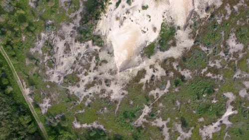 Aerial view of a sandy area surrounded by green vegetation and trees, showcasing a natural landscape