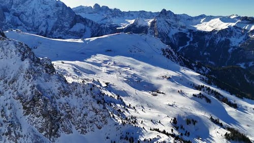 Ski piste in the Italian Dolomites surrounded by mountains during winter season (drone footage)