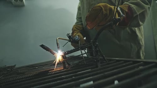 Man Welding Metal Parts in Workshop