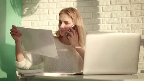 Smiling Woman Working from Home with Laptop and Documents