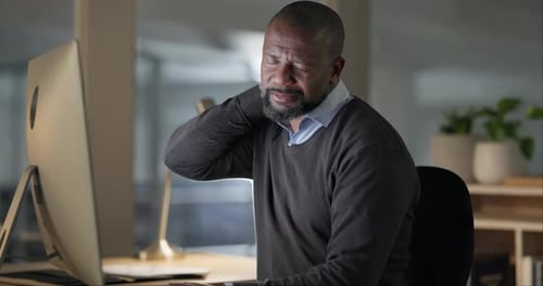 Man Massages Aching Neck at Office Desk