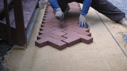 Man Creating Red Brick Walkway with Tool