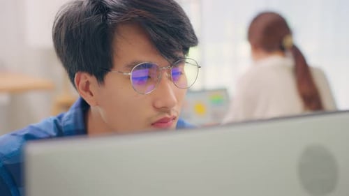 Exhausted Asain business man using laptop computer working in office.