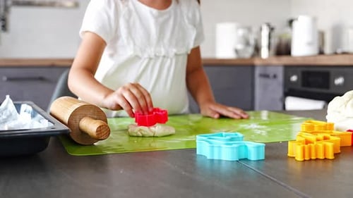 Child Baking Cookies in Kitchen with Cookie Cutters