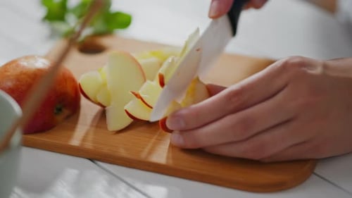 Hands Cutting Red Apple Slices on Cutting Board