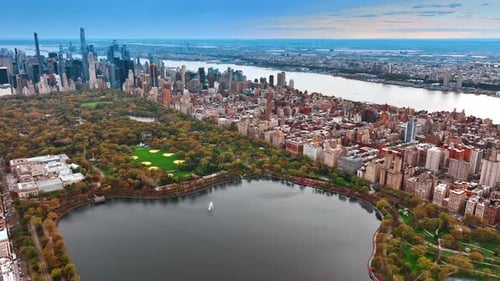 Approaching the panorama of a pond in green Central Park in New York downtown.