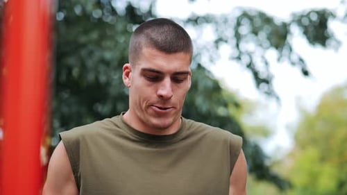 Young athletic man doing push-ups at red sports facility in park
